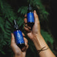 both hands holding a bottle of intention oil and clarity mist infused with blue lotus
