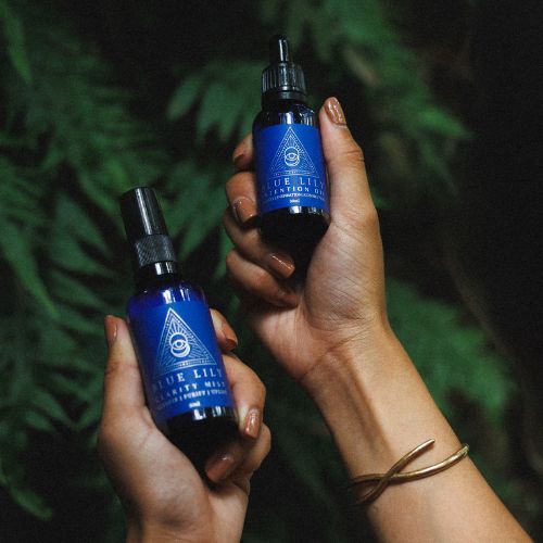 both hands holding a bottle of intention oil and clarity mist infused with blue lotus